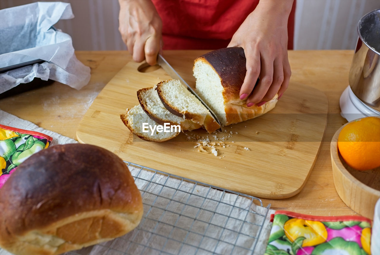 Close-up of woman cutting bread in kitchen