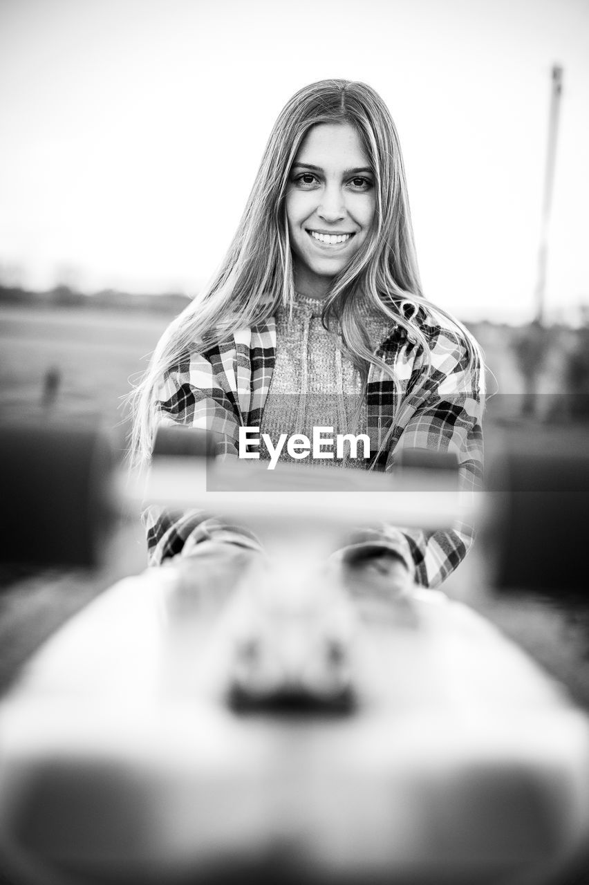 Portrait of smiling woman holding skateboard