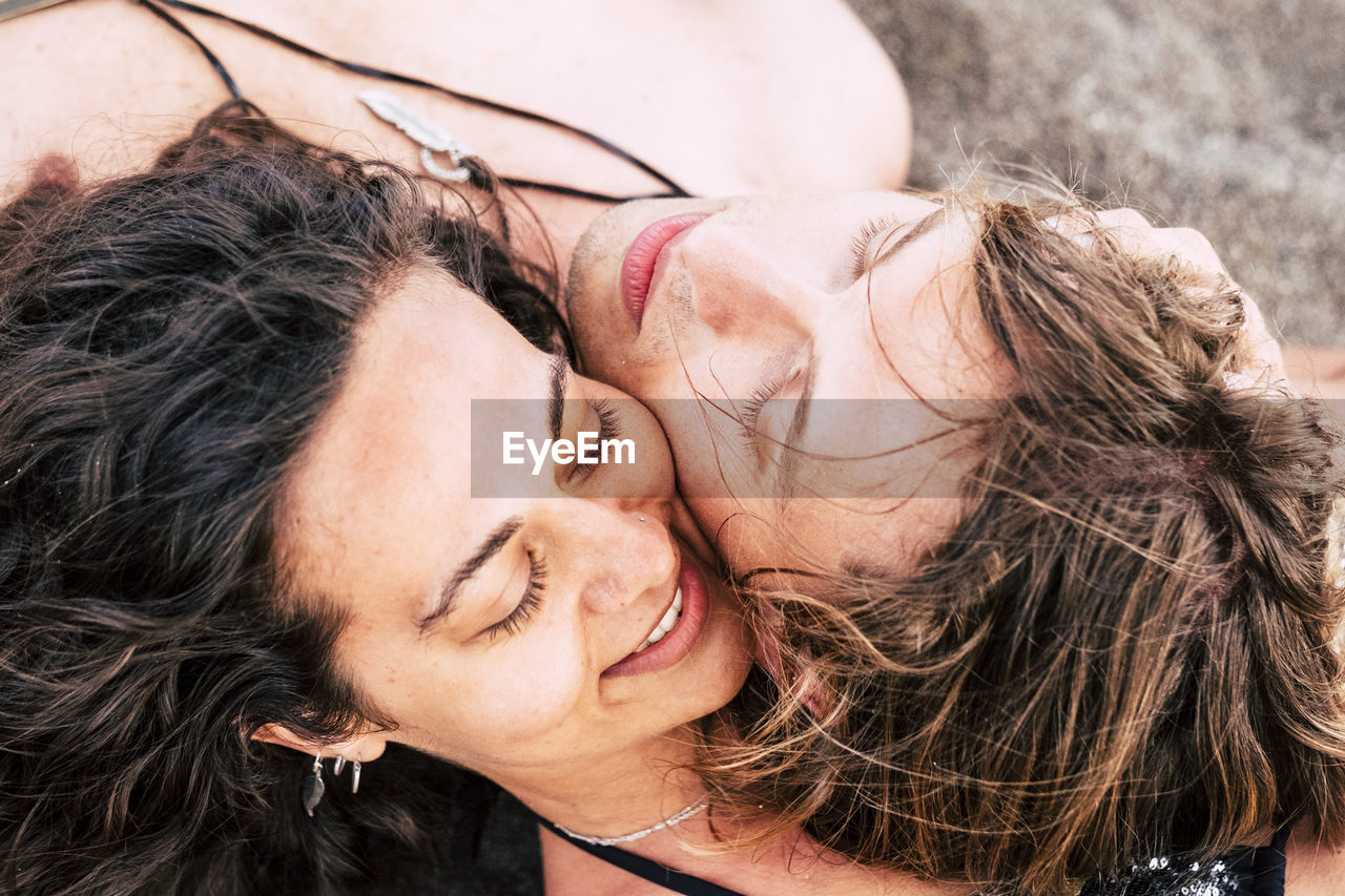 Close-up of smiling man and woman lying on sand at beach