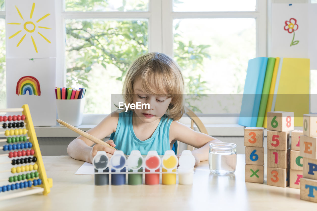 Funny beautiful happy child boy draws laughing with paint.