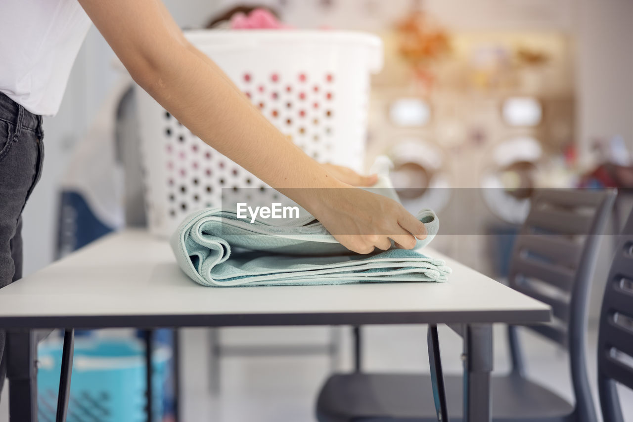 MIDSECTION OF WOMAN ON TABLE IN KITCHEN