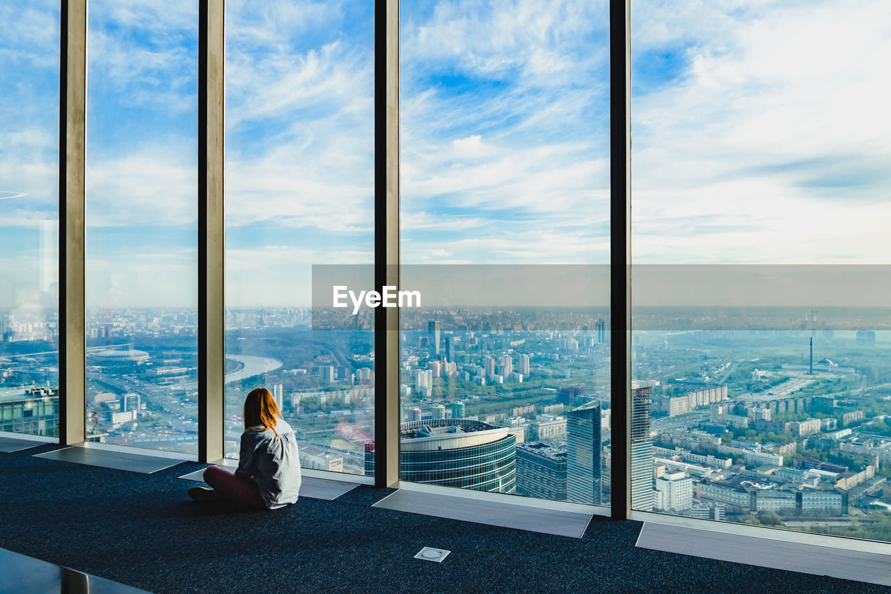 WOMAN SITTING BY WINDOW