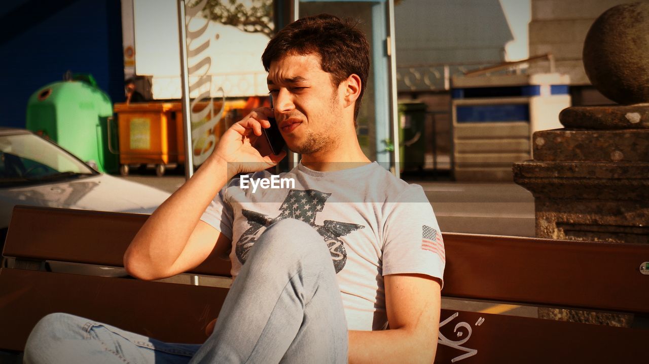 Man talking on mobile phone at bench