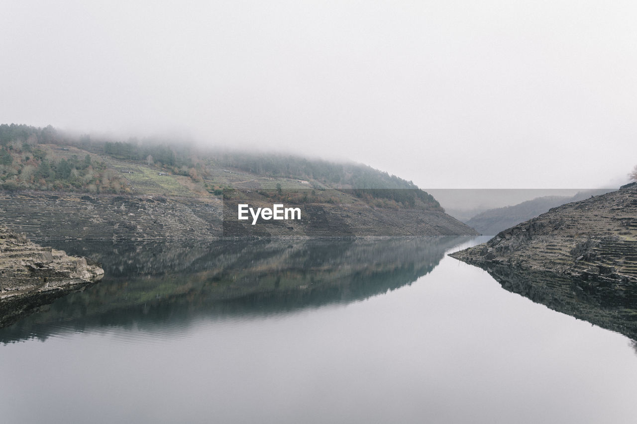 Scenic view of lake by mountains against sky