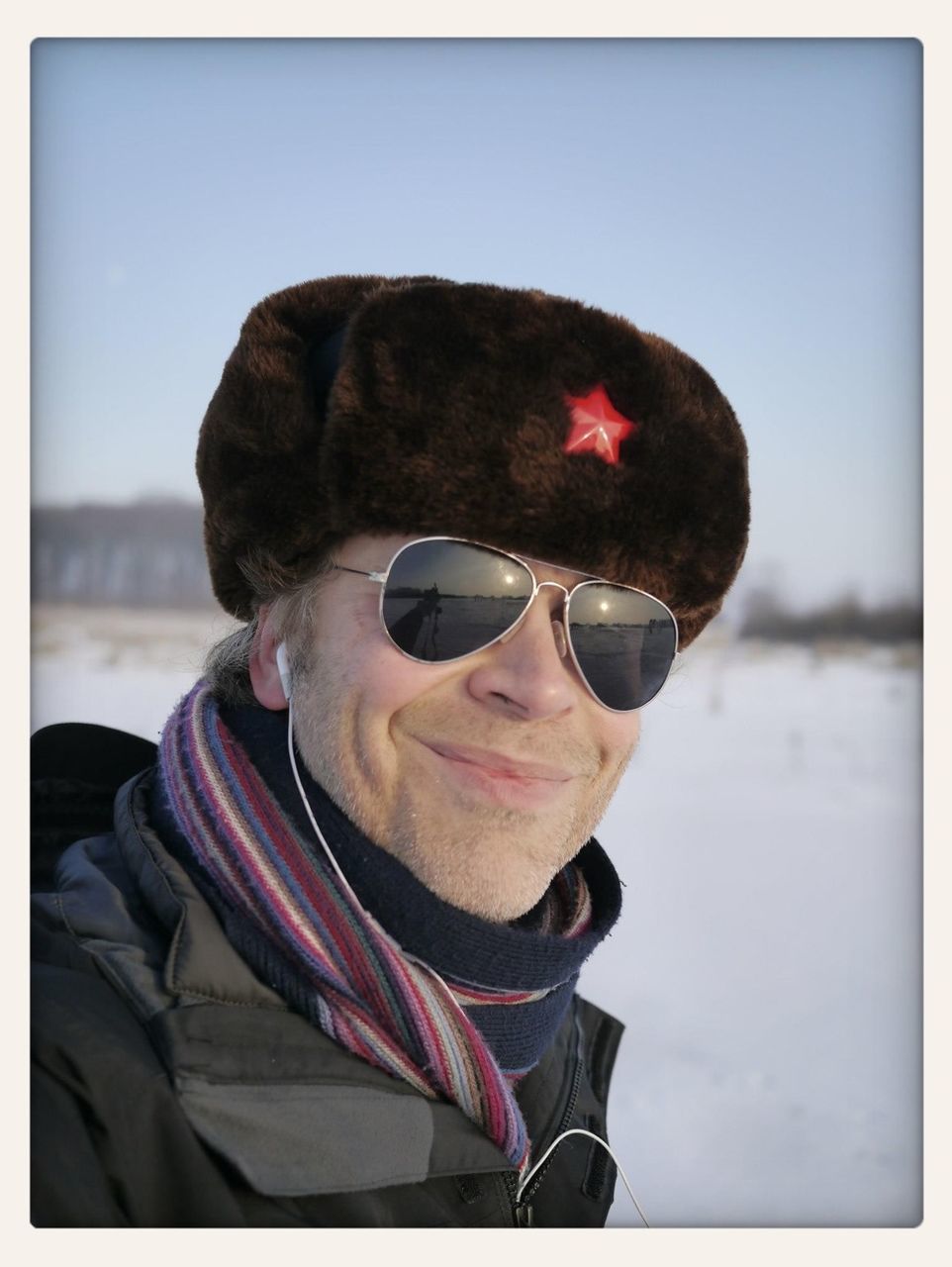 Portrait of smiling mid adult man on snowy field against clear sky