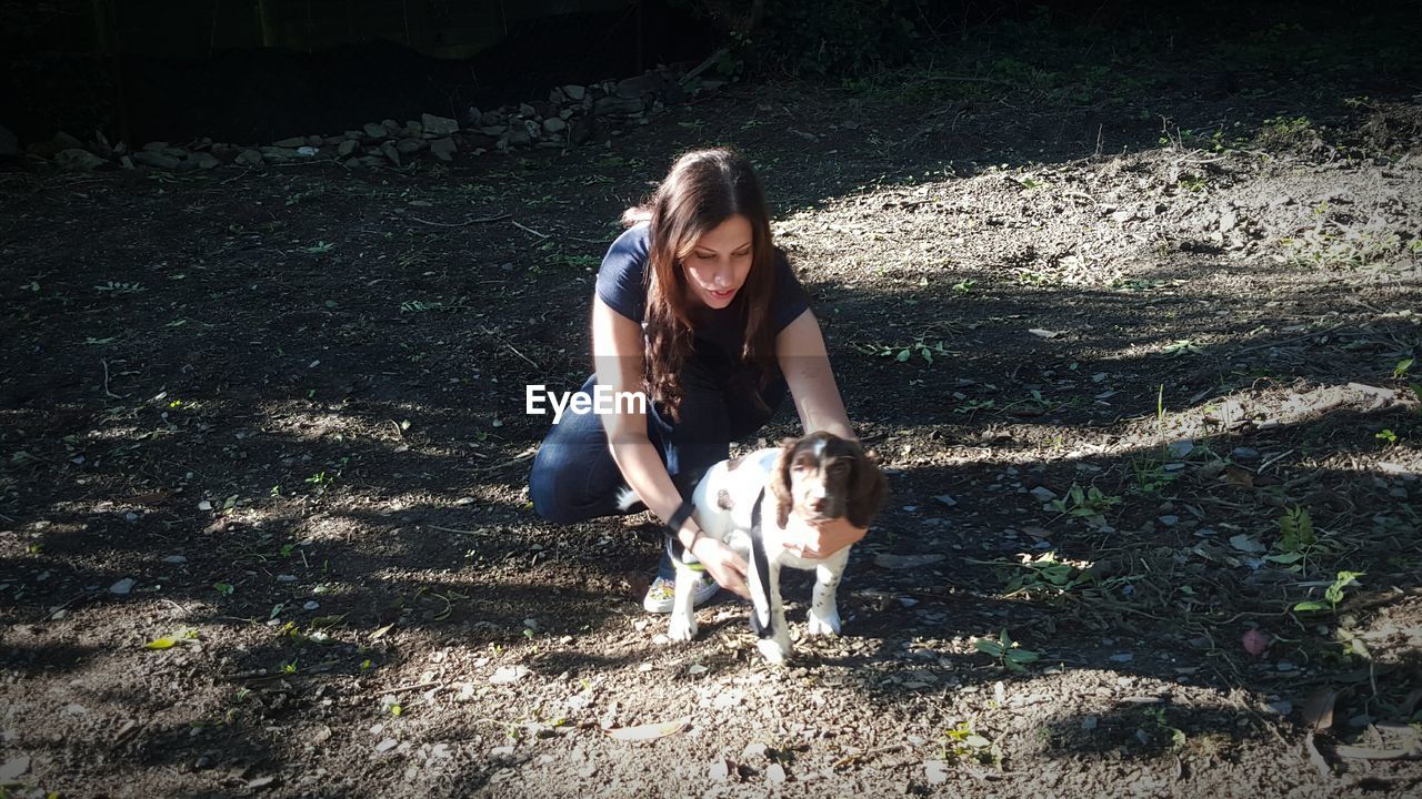 High angle view of woman with dog crouching on field