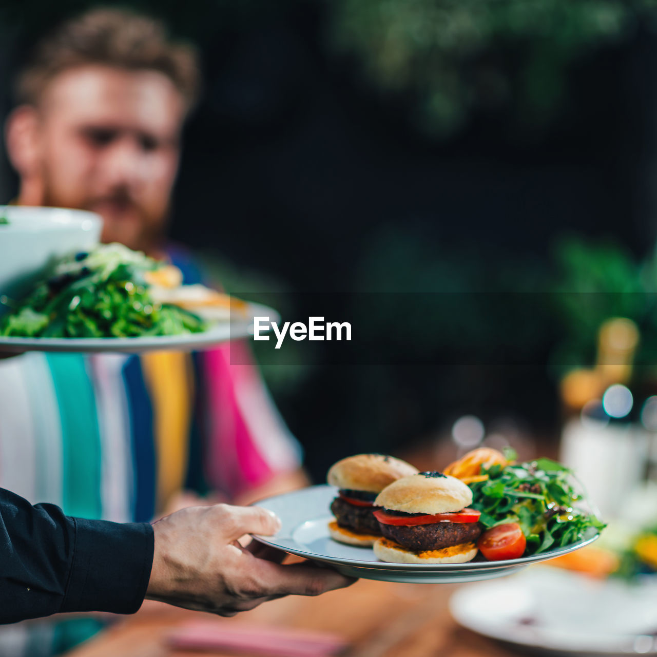 Cropped hand of waiter keeping food on table in restaurant