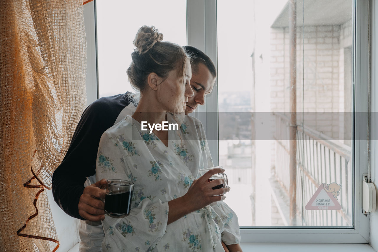 Woman looking away while sitting on window