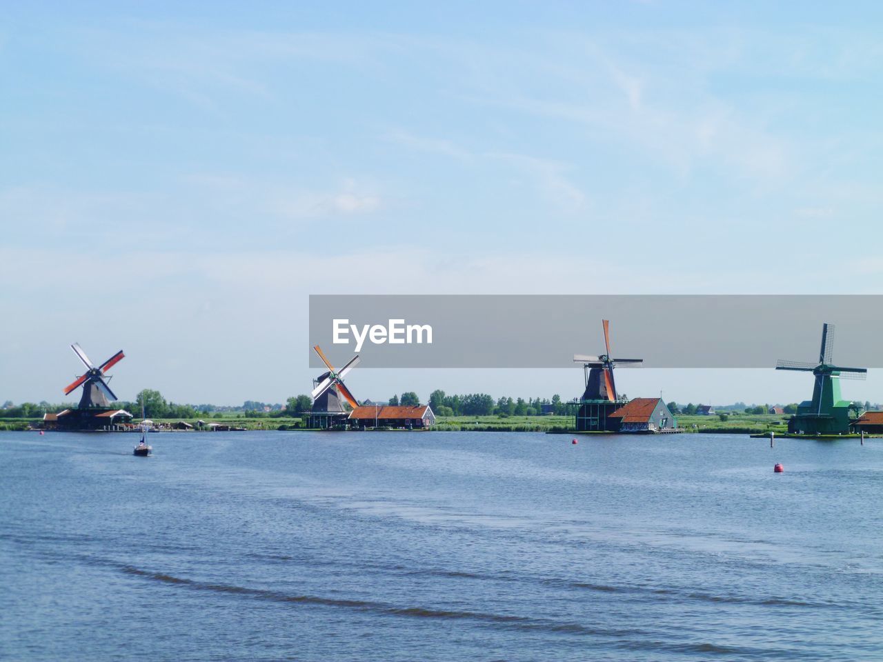 Scenic view of sea against sky and windmills