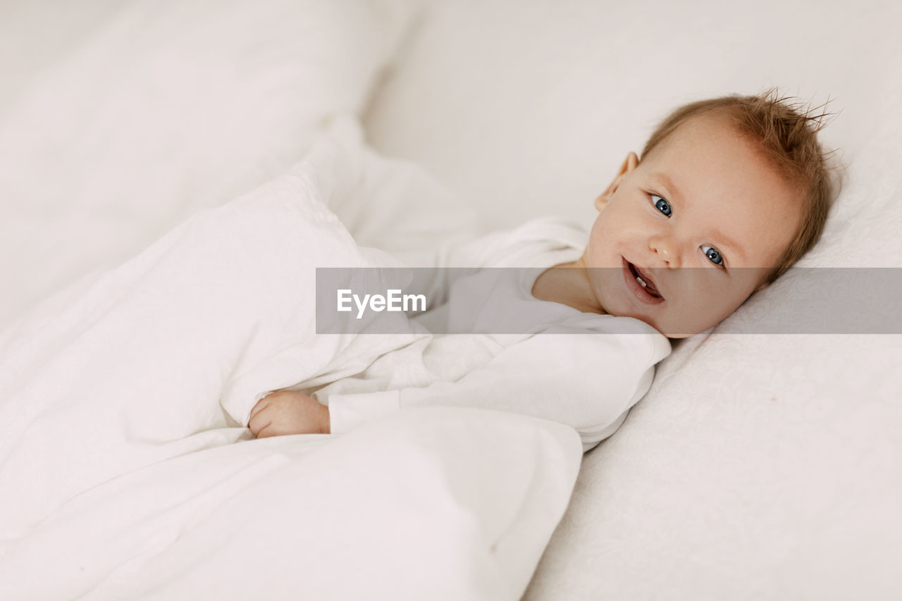 Portrait of cute baby lying on bed