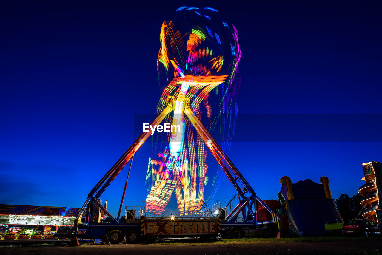 LOW ANGLE VIEW OF ILLUMINATED FERRIS WHEEL AGAINST SKY