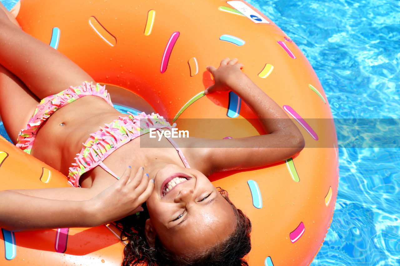 Portrait of smiling woman lying in on pool raft in swimming pool