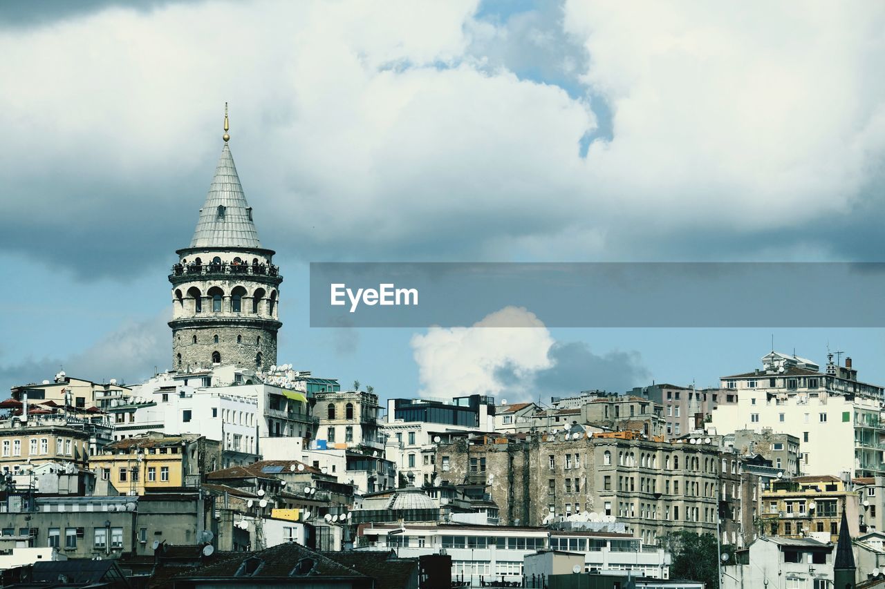Buildings in karaköy city and galata tower  against cloudy sky