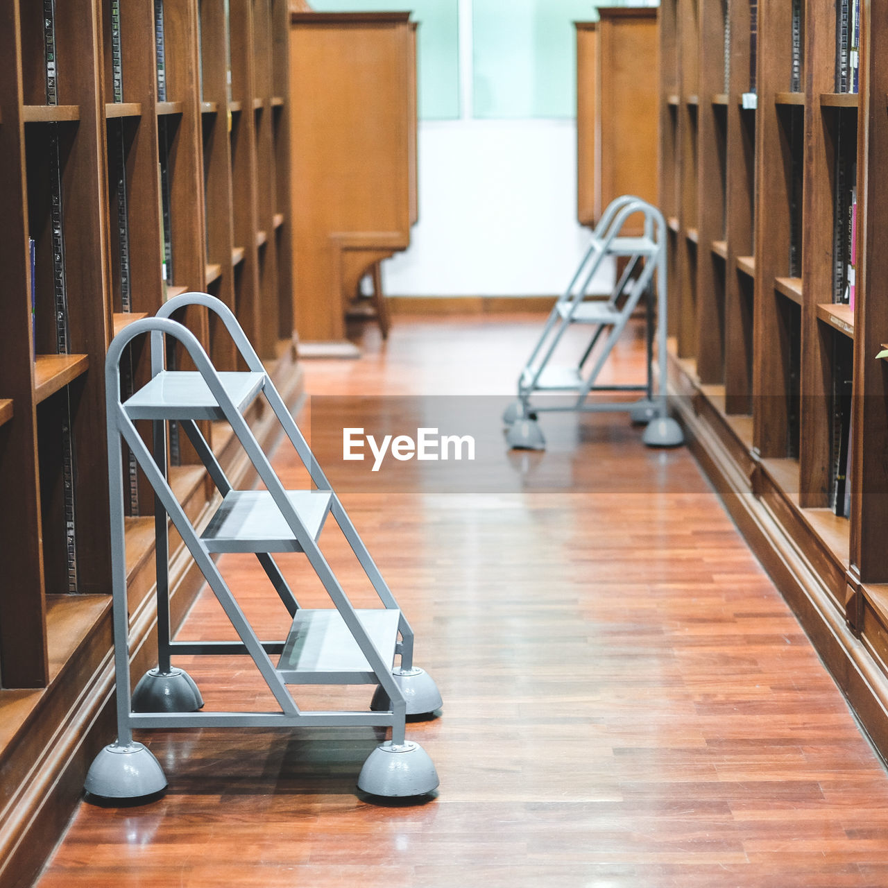 Ladders amidst bookshelves in library