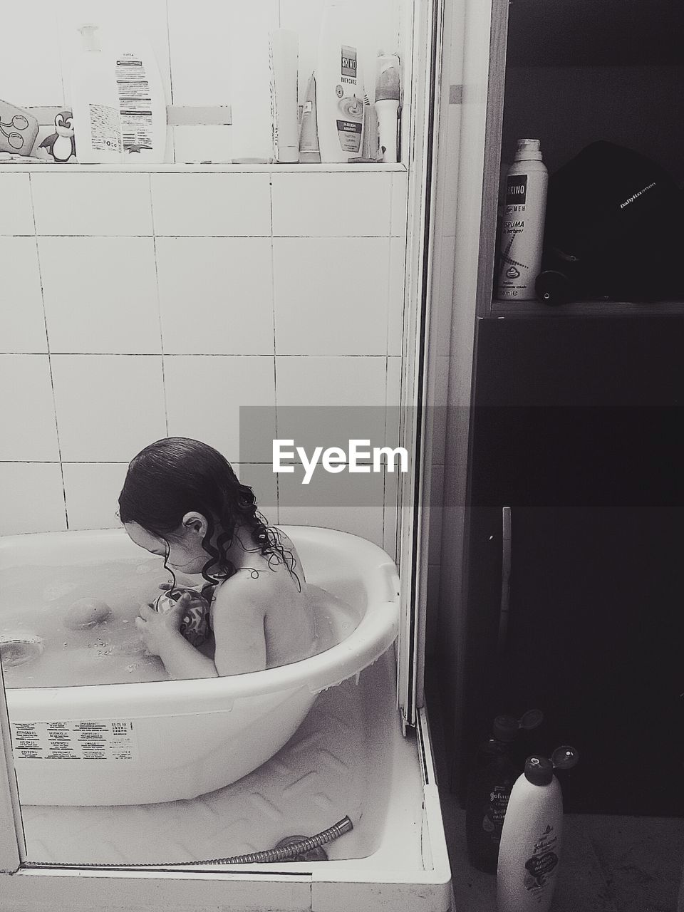High angle view of baby girl with ball in bathtub at home