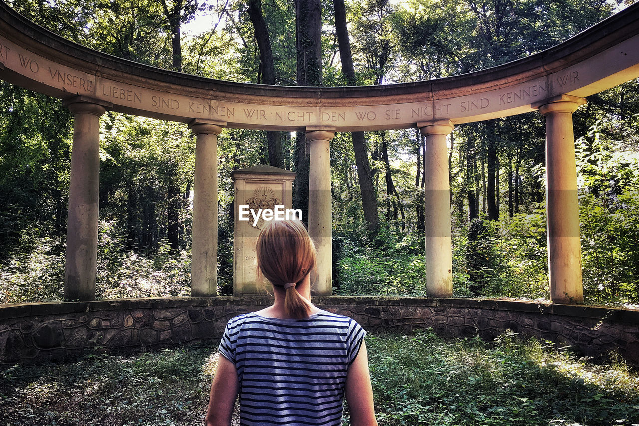 Rear view of woman standing at forest