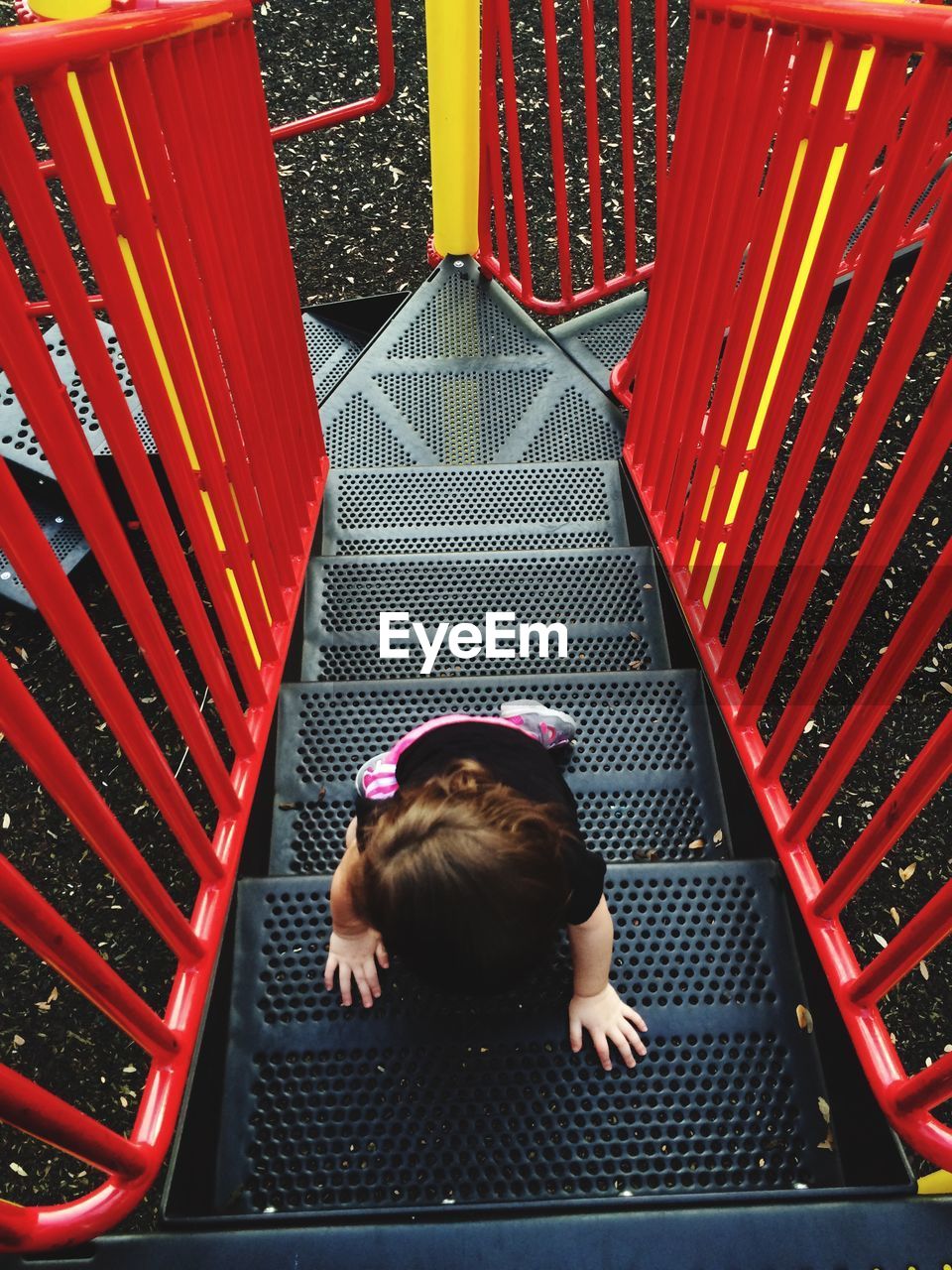 High angle view of preschool girl climbing steps at playground