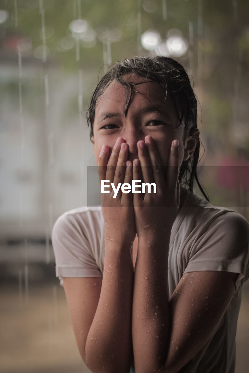 Portrait of girl covering mouth during rainy season