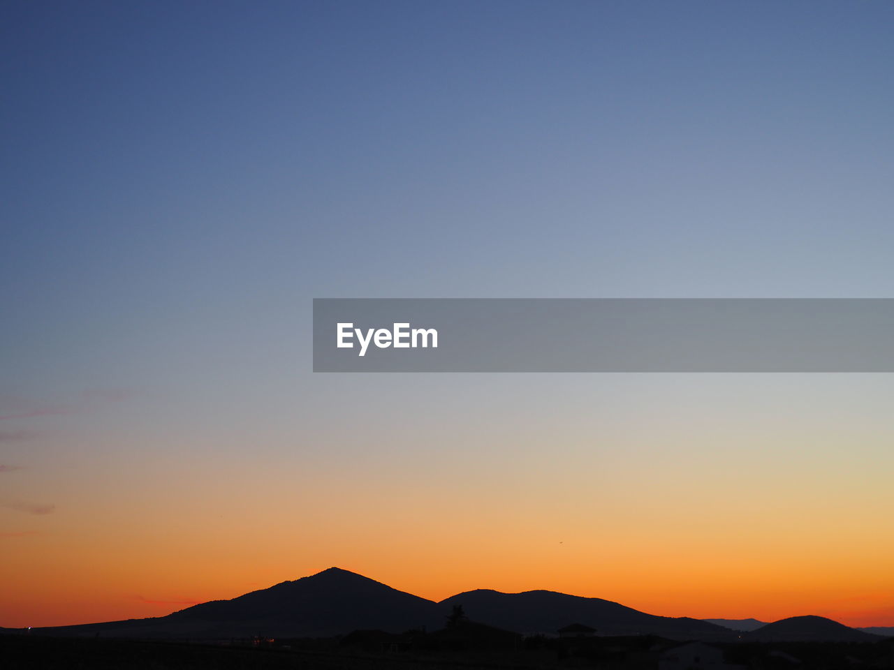 Scenic view of silhouette mountains against clear sky during sunset