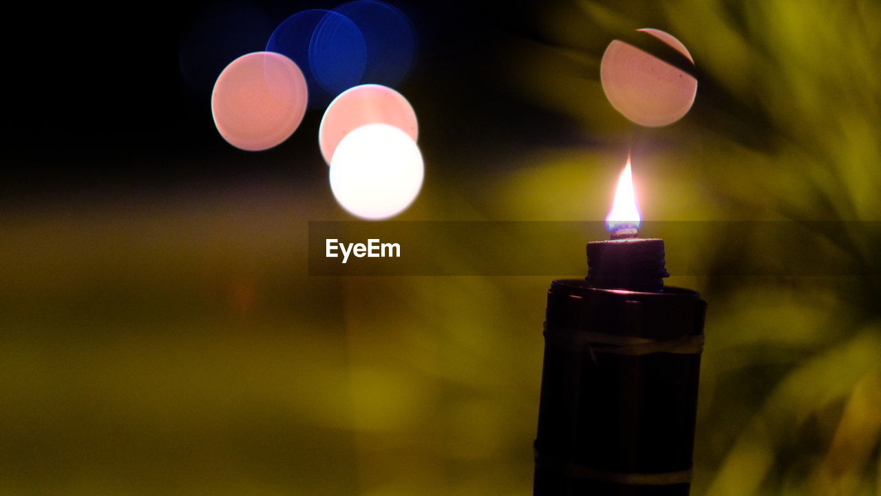 Close-up of burning flamed kerosene lamp with light bokeh