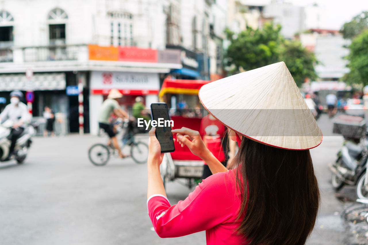 young woman using mobile phone while standing in city