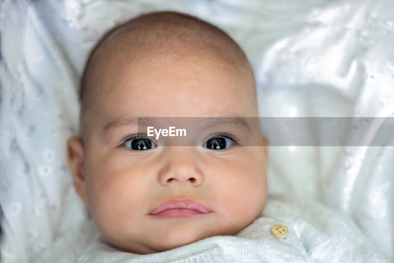 Close-up portrait of cute baby lying on bed