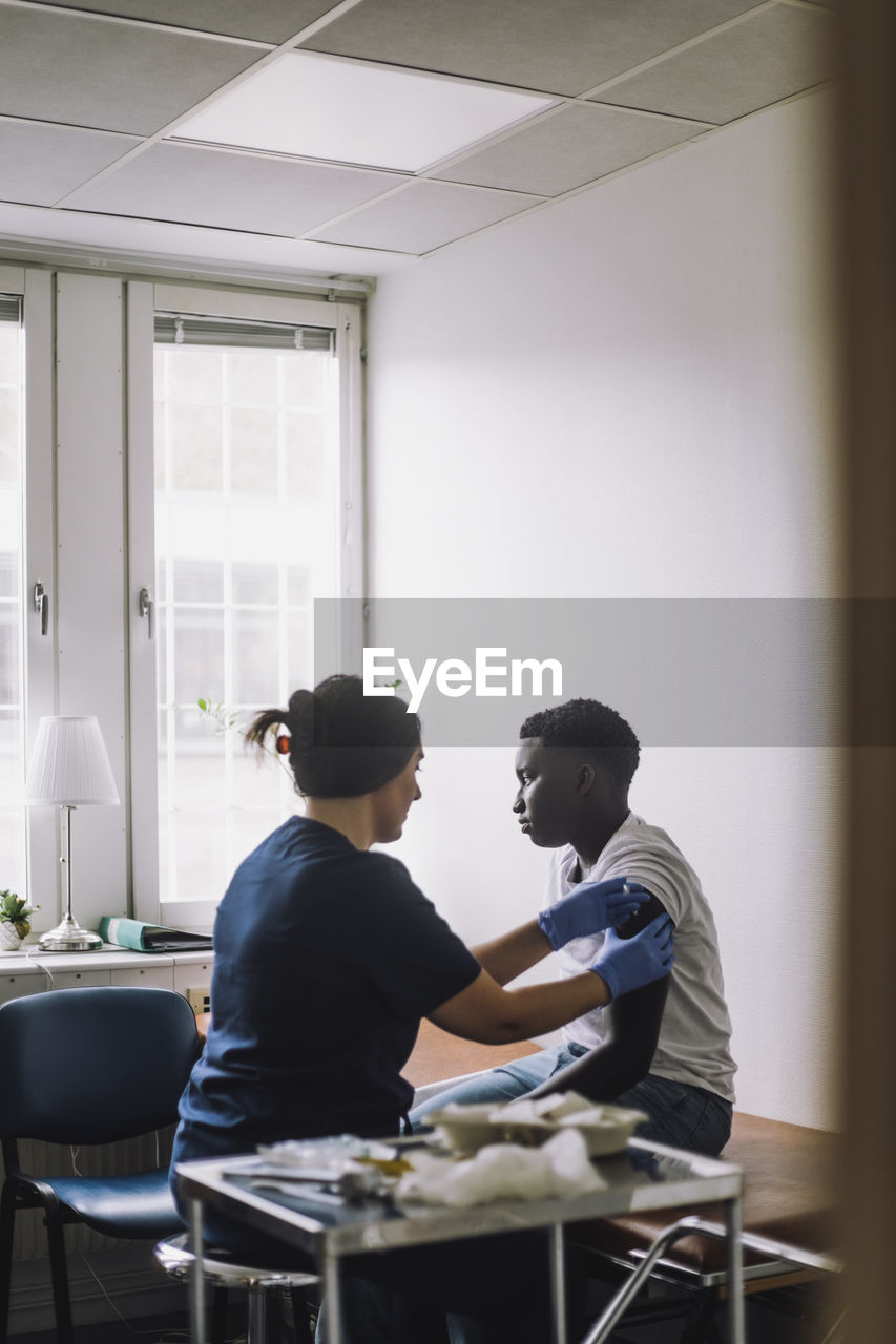 Teenage male patient taking vaccination on arm at hospital