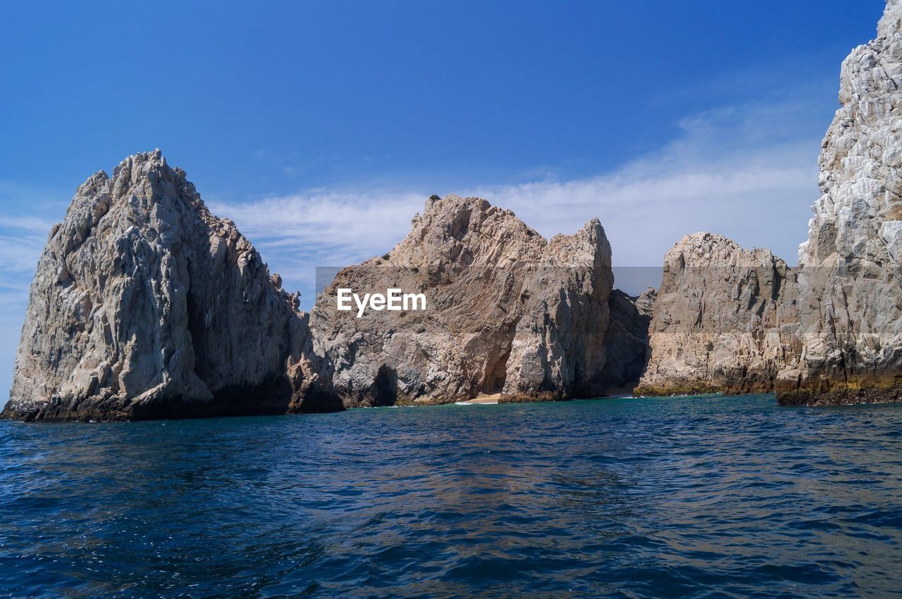 Panoramic view of sea and rocks against blue sky