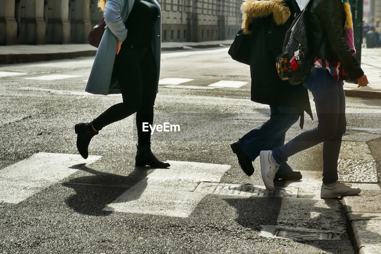 Low section of people walking on street in city