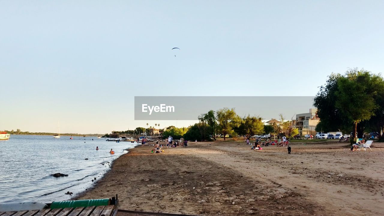 PEOPLE AT BEACH AGAINST SKY