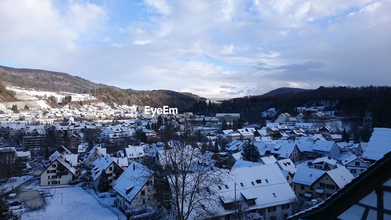 Snow covered residential district against cloudy sky