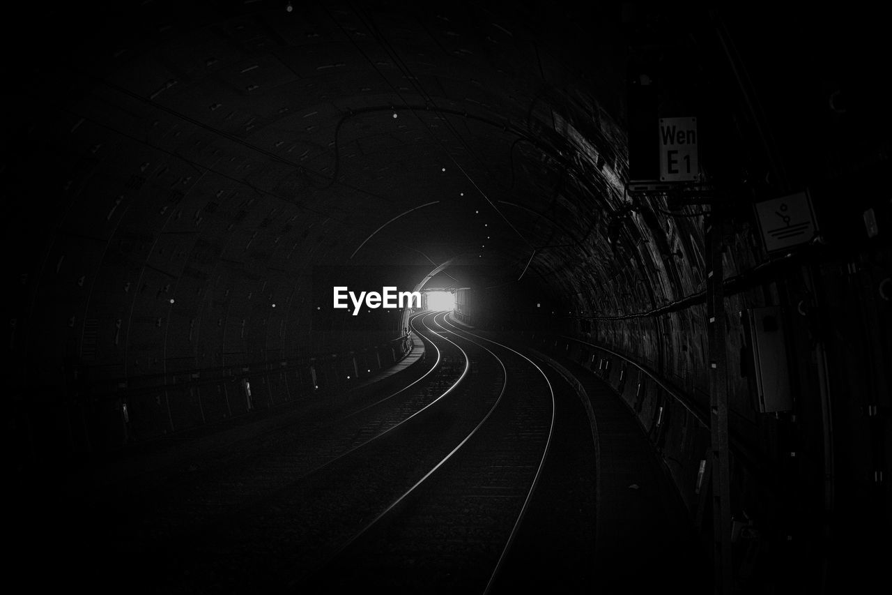 darkness, tunnel, black and white, night, transportation, monochrome, black, track, railroad track, light, rail transportation, monochrome photography, no people, architecture, line, mode of transportation, illuminated, the way forward, public transportation, infrastructure, built structure, road, city, dark, outdoors, motion, curve