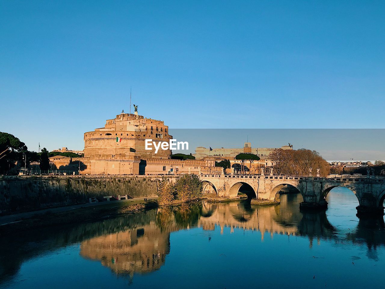 ARCH BRIDGE OVER RIVER AND BUILDINGS AGAINST BLUE SKY
