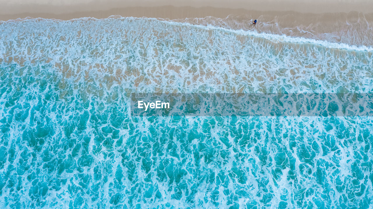 Aerial top view of sandy beach with travelling tourists in beautiful the sea wave 