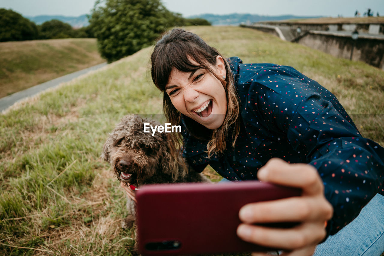 Woman taking selfie with dog on field