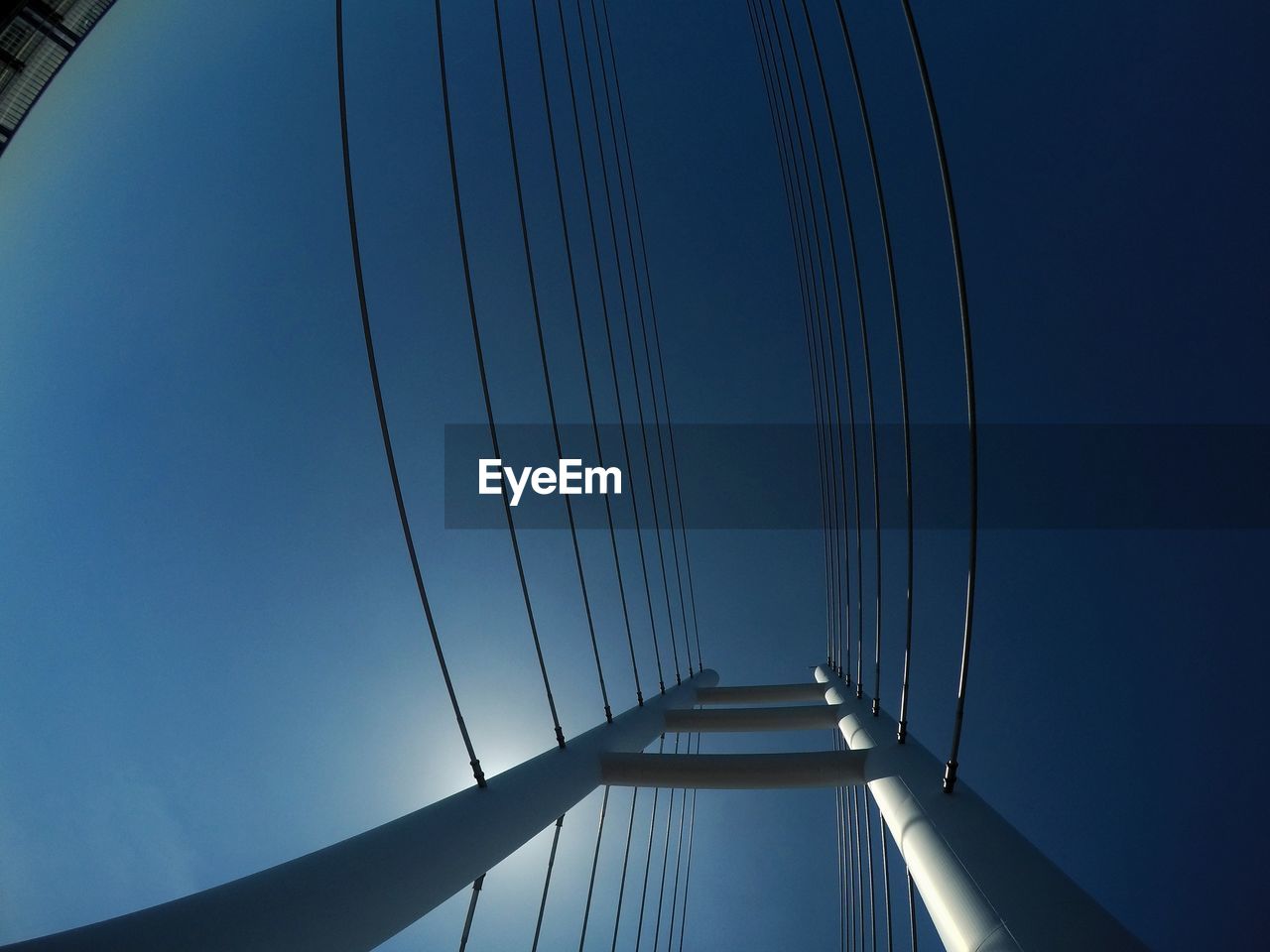 LOW ANGLE VIEW OF SUSPENSION BRIDGE CABLES AGAINST BLUE SKY