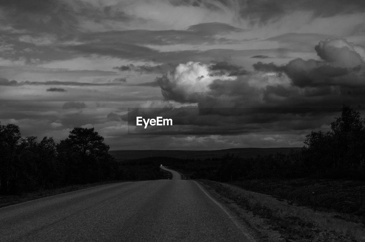 cloud, sky, black and white, road, transportation, darkness, monochrome, environment, the way forward, nature, monochrome photography, landscape, plant, tree, horizon, beauty in nature, scenics - nature, no people, land, storm, black, vanishing point, sign, storm cloud, dramatic sky, rural scene, diminishing perspective, non-urban scene, cloudscape, outdoors, tranquility, dusk, tranquil scene, overcast, field, thunderstorm, country road, remote, dark, travel