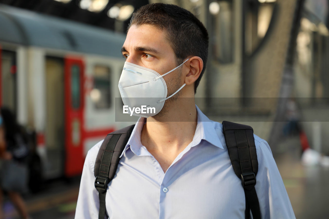 Close-up of man wearing flu mask standing on railroad station platform