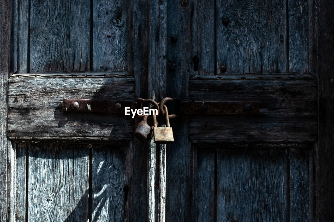 Close-up of padlocks hanging on wooden door