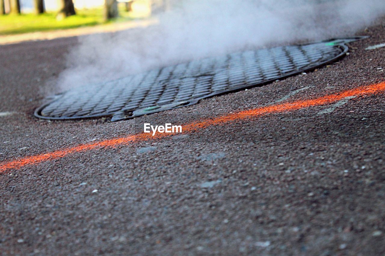 Close-up of steam from manhole lid on road