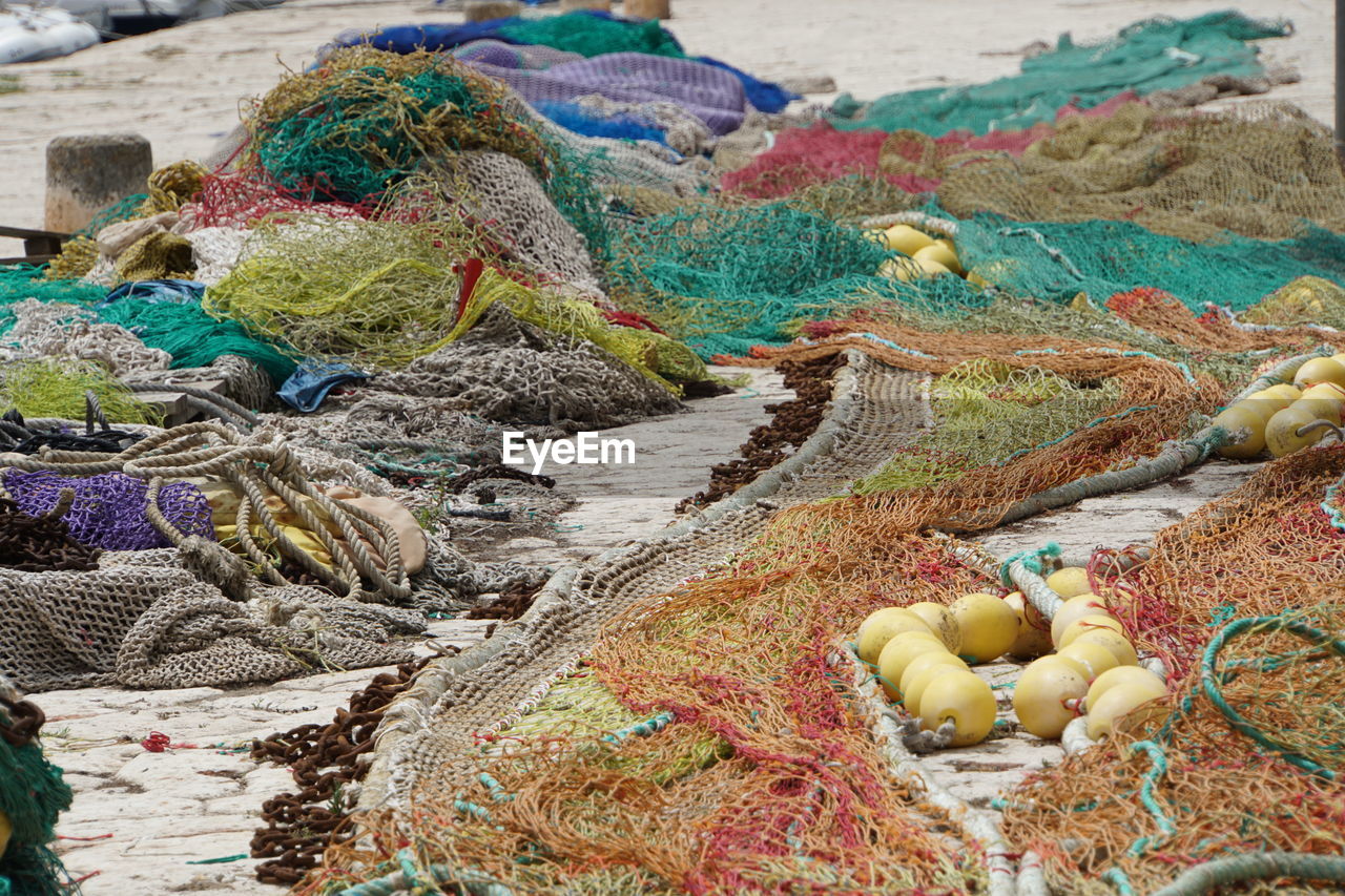 fishing net, commercial fishing net, fishing industry, fishing, rope, no people, fishing rod, day, multi colored, buoy, rod, large group of objects, abundance, harbor, outdoors, high angle view, netting, variation, still life, nature