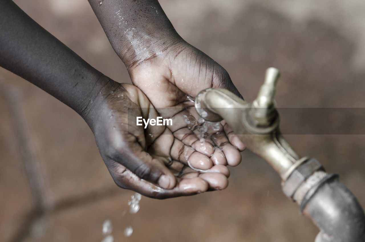 Close-up of hands under falling water from faucet