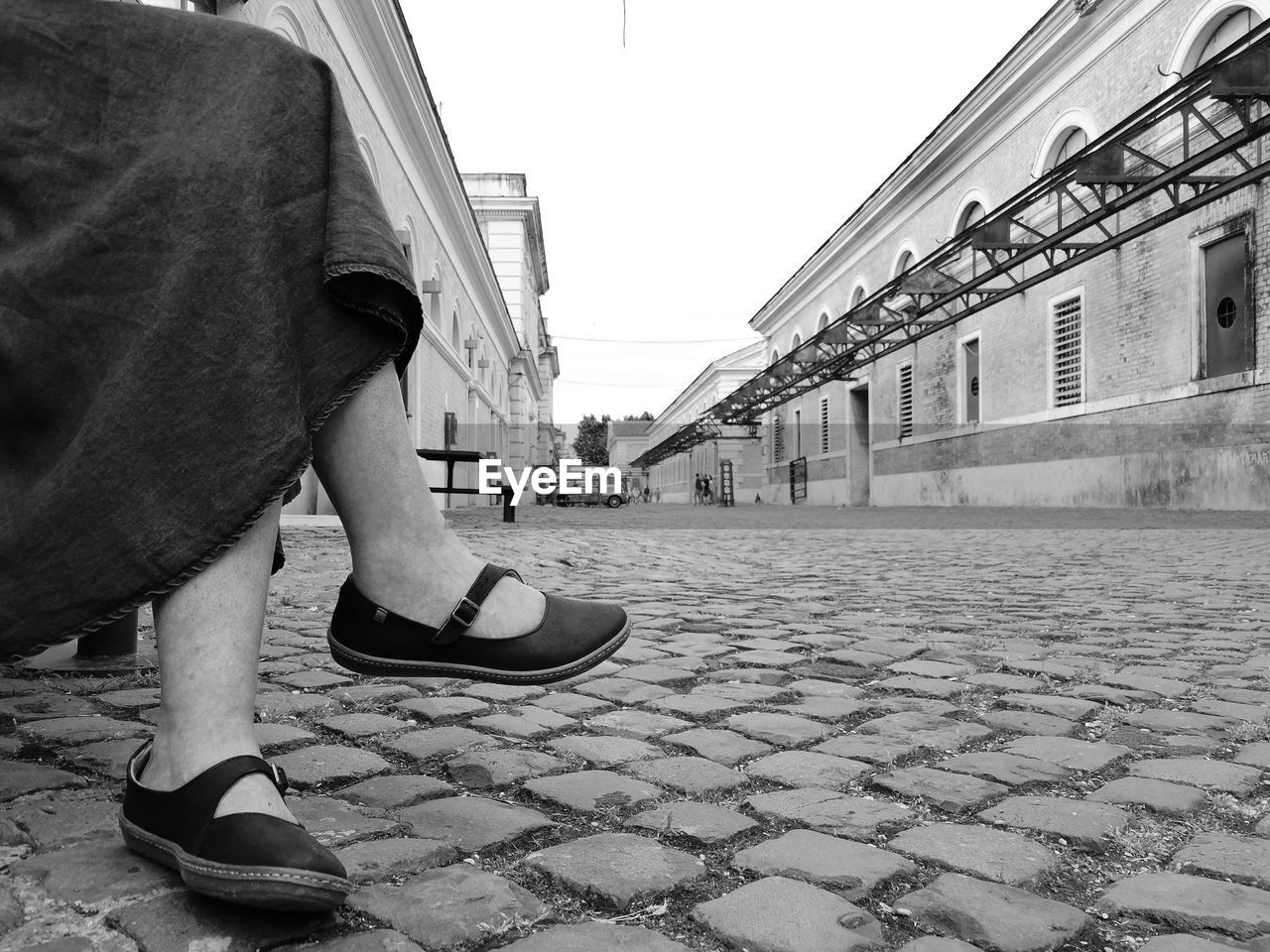 LOW SECTION OF MAN STANDING ON FOOTPATH BY STREET