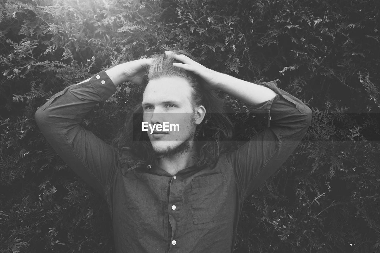 Young man with hand hair standing by plants