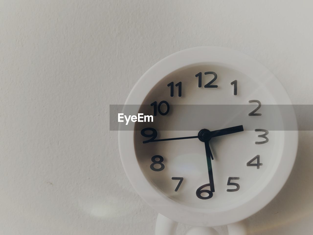 CLOSE-UP OF CLOCK ON WHITE WALL