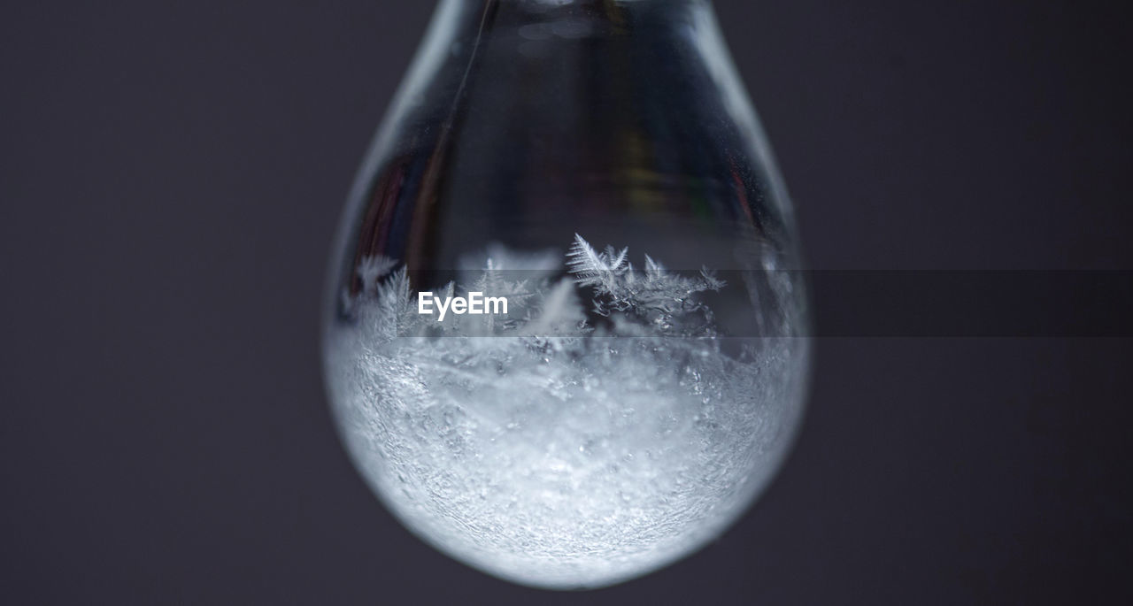 Macro shot of snowflakes reflection on drop against gray background