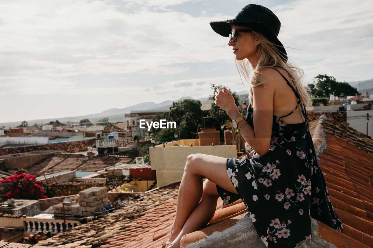 Side view of smiling woman sitting on rooftop