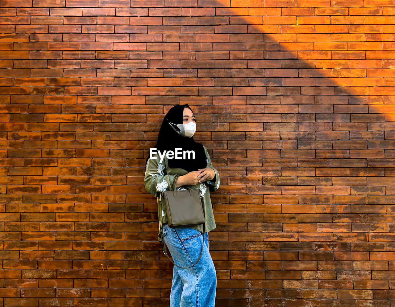 Young woman standing against brick wall