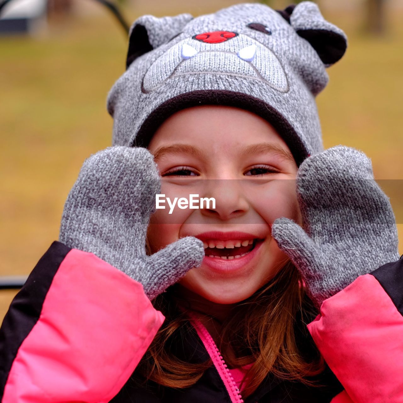 Close-up portrait of smiling girl wearing knit hat and gloves