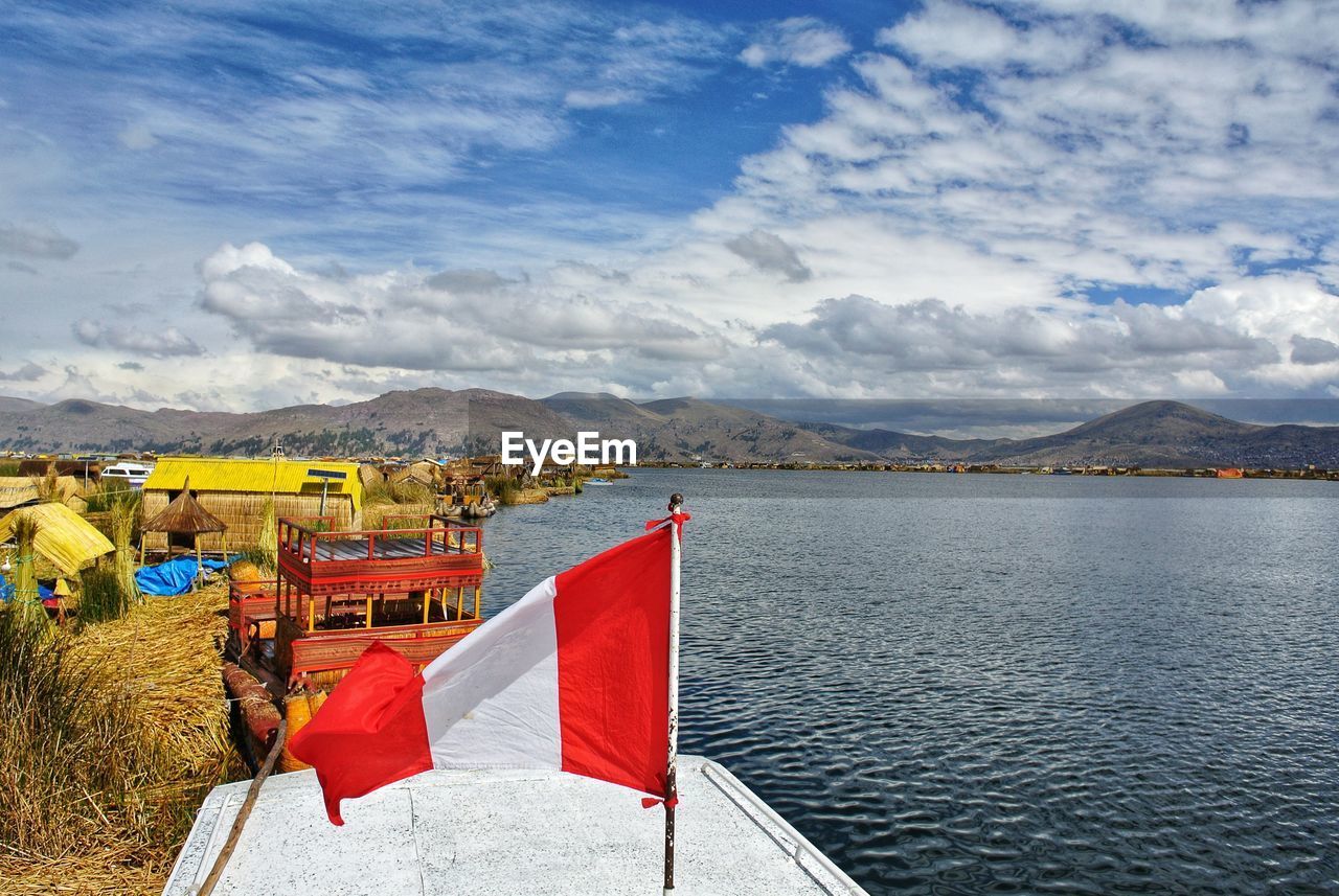 Scenic view of flag by lake against sky
